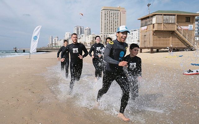 Ha'Gal Sheli co-founder Yaron Waksman (front) leading a surfing lesson for at-risk teenagers in Tel Aviv.