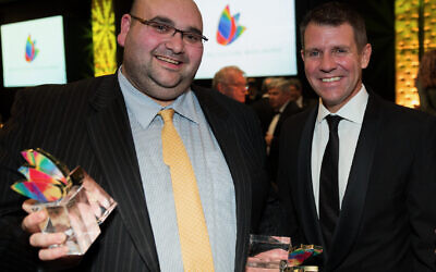 Joshua Levi with the multiple trophies he won at the NSW Premier's Multicultural Media Awards in 2016, alongside then-premier Mike Baird.