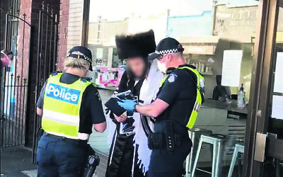 Police speak to an attendee of an illegal minyan in April. Photo: Facebook
