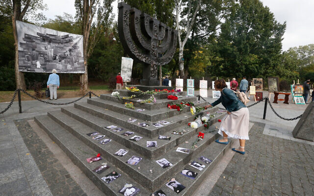 A woman lays flowers at a menorah monument close to the Babi Yar ravine where tens of thousands of Jews were killed during WWII. Photo: AP Photo/Efrem Lukatsky