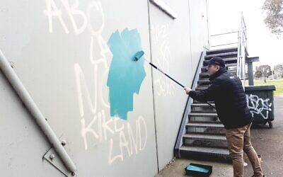 AJAX Football Club president Ronnie Lewis removing the graffiti on Sunday. Photo: Peter Haskin