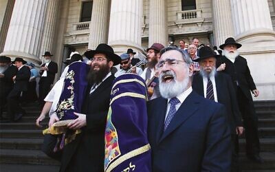 Rabbi Jonathan Sacks and Rabbi Dovid Gutnick (left) lead a procession from Parliament to East Melbourne Shule, following a double Torah dedication in 2012. Photo: Peter Haskin