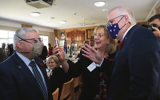 Prime Minister Scott Morrison (right) with Felix and Yvonne Sher waving at the couple's grandchildren over FaceTime. Photo: Peter Haskin