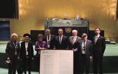 Gilad Erdan holds an enlarged copy of the resolution, flanked by Holocaust survivors at the UN General Assembly. 
Photo: Israel's Mission to the UN