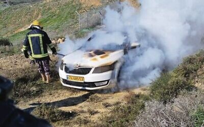 A firefighter douses the flames in an Israeli car after it was allegedly set on fire by Jewish extremists near Givat Ronen last month. Photo: Courtesy, Yesh Din
