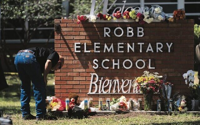 A law enforcement officer lights a candle outside Robb Elementary School in Uvalde, Texas, last week. 
Photo: AP/Jae C. Hong