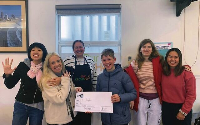 JCA's Lauren Finn (second from left) accepts Liel Rapke's bar mitzvah donation during his time volunteering at Our Kitchen Hand.