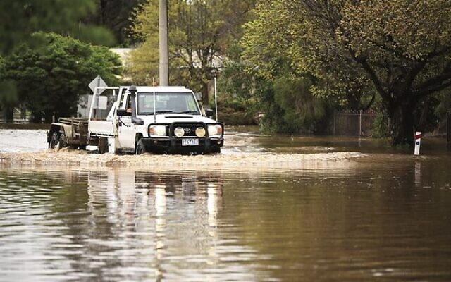 A vehicle driving through flood water on a residential street in flooded rural Victoria last Friday. Photo: AAP Image/James Ross