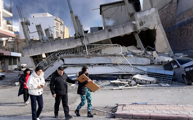 People pass a destroyed building, in Iskenderun town, southern Turkey.  Photo: AP Photo/Hussein Malla via Times of Israel