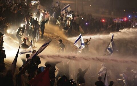 Israeli police use a water cannon to disperse demonstrators blocking a highway during a protest in Tel Aviv. 
Photo: AP/Oren Ziv