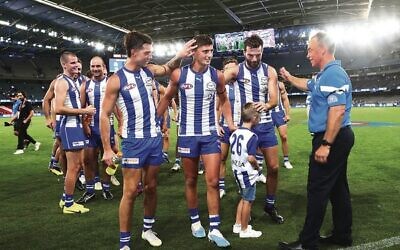 Harry Sheezel (centre) is congratulated by teammates, and Kangaroos coach Alastair Clarkson (right), after North Melbourne's round one win over the Eagles at Marvel Stadium last Saturday. Photos: Peter Haskin