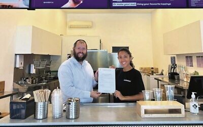 Rabbi Aaron Groner presenting the Certificate of Kashrut to the new store in Rose Bay. Photo: Facebook.
