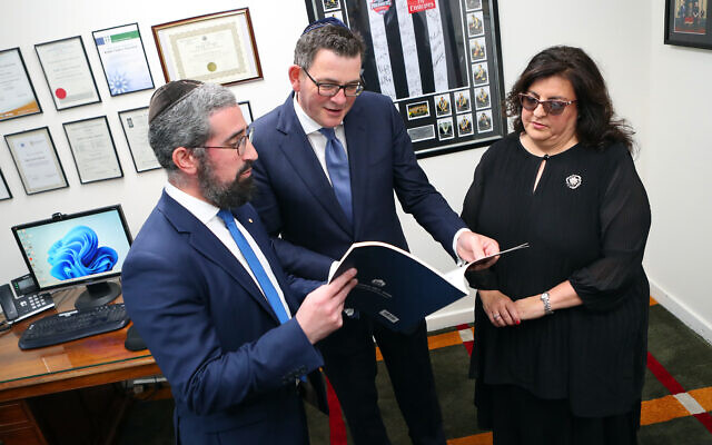 Premier Daniel Andrews (centre), Rabbi Yaakov Glasman and Janice Iloni-Furstenberg, president of St Kilda Shule, study a book about the synagogue's 150 years. Photo: Peter Haskin