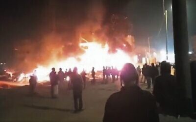 Settlers pray as cars and homes burn in Huwara on February 26. 
Photo: Screenshot/Twitter