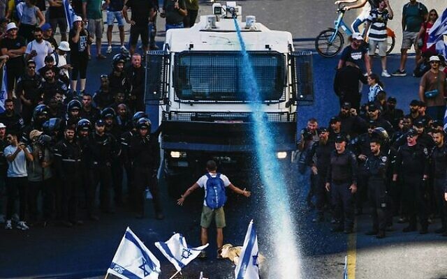 A person stands in front of a water cannon during a protest in Jerusalem on Monday. Photo: AP/Ariel Schalit