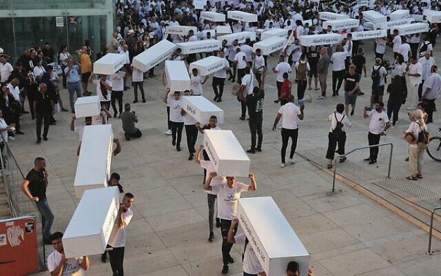 Activists in Tel Aviv march with symbolic coffins denouncing the violent crimes against Arab communities. 
Photo: Jack Guez / AFP