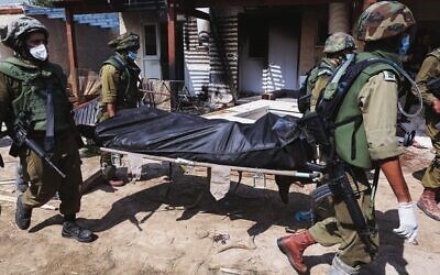 IDF soldiers remove the body of an Israeli killed by Hamas terrorists in Kibbutz Kfar Aza, on October 10. 	Photo: Jack Guez/AFP