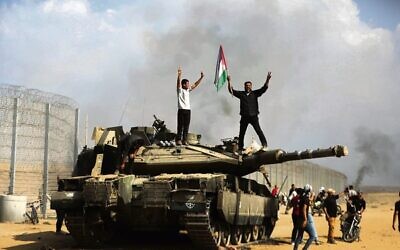 Gazans celebrate on a destroyed Israeli tank at the Israel-Gaza border fence on October 7. 
Photo: AP/Yousef Masoud