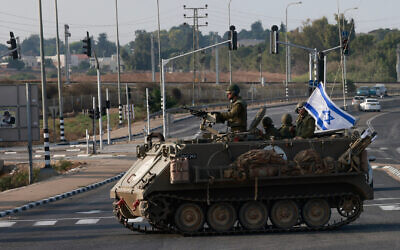 Israeli forces cross a main road in an armored personnel carrier (APC) as additional IDF troops are deployed near the southern city of Sderot following an assault by Hamas terrorists, October 8, 2023. (Menahem KAHANA/AFP)