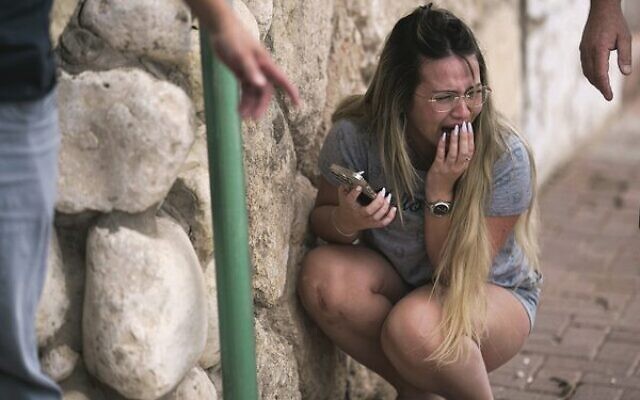 A young Israeli woman takes cover from incoming rocket fire from the Gaza Strip in Ashkelon, southern Israel. Photo: AP Photo/Leo Correa