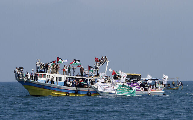 FILE: Palestinians waving national flags wait aboard small boats off the port of Gaza City on May 30, 2010, to greet the so-called 'Freedom Flotilla.' (The Times of Israel: MAHMUD HAMS / AFP)