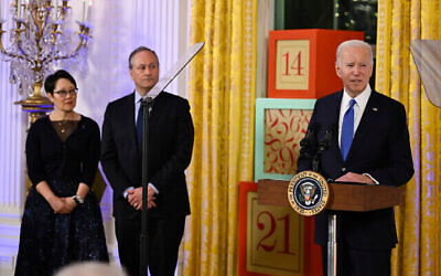 US President Joe Biden speaks at a Hanukkah reception in the East Room of the White House in Washington, Monday, Dec. 11, 2023, as second gentleman Doug Emhoff and Rabbi Angela Buchdahl listen. (The Times of Israel: Andrew Caballero-Reynolds/Pool via AP)