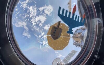 A dreidel spins in zero gravity in front of a makeshift menorah aboard the International Space Station in a video shared by NASA Astronaut Jasmine Moghbeli on December 8, 2023. (The Times of Israel: Twitter screenshot, used in accordance with Clause 27a of the Copyright Law)