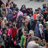 Displaced Palestinians gather to receive food at a government school in Rafah in the southern Gaza Strip on February 19, 2024. (The Times of Israel: Mohammed Abed/AFP)