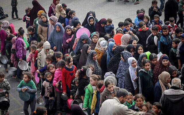 Displaced Palestinians gather to receive food at a government school in Rafah in the southern Gaza Strip on February 19, 2024. (The Times of Israel: Mohammed Abed/AFP)