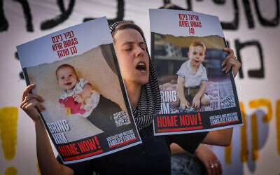 An Israeli student holds pictures of hostages during a protest calling for their release near the Knesset in Jerusalem, June 13, 2024. (The Times of Israel: Chaim Goldberg/Flash90)