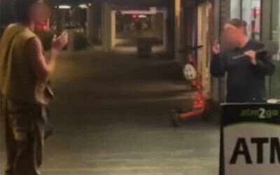 A screenshot from video footage of the incident. One of the Israeli tourists is on the left, and on the right is the shop attendant, holding what appears to be a club or shovel. Their faces have been blurred.