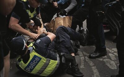 A police officer is tackled after trying to arrest a protester, in Melbourne on October 20, 2025Photo: AAP by Gemma Hubeek / SOPA images/Sipa USA.
