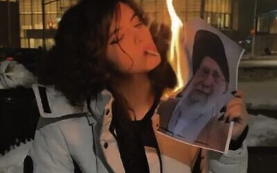 An Iranian woman lights a cigarette from a burning picture of Supreme leader Ayatollah Ali Khamenei in what has become an iconic image.