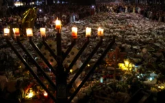 A menorah is pictured after the seventh candle is lit for the Jewish festival of Hanukkah as mourners stand next to floral tributes laid out in memory of the victims of a shooting attack at Bondi Beach, in Sydney, December 20, 2025. (David Gray / AFP)