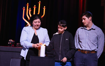Prof Sabina Kleitman, Michael and Matthew Tretyakov lighting a candle in honour of their father and grandfather Holocaust survivor Alex Kleytman who was killed in the Bondi Chanukah terrorist attack. Photo: Giselle Haber