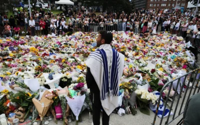 Rabbi Yossi Friedman speaks to people gathering at a flower memorial by the Bondi Pavilion at Bondi Beach, December 16, 2025, following Sunday's antisemitic terror attack in Sydney, Australia. (AP Photo/Mark Baker)