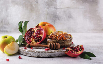 Rosh Hashana Jewish New Year concept with honey, apple and pomegranate. Photo: Magnific.com