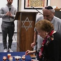 Serena Feldman lighting a candle at a 2022 Yom Hashoah service at COA.
