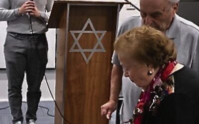 Serena Feldman lighting a candle at a 2022 Yom Hashoah service at COA.