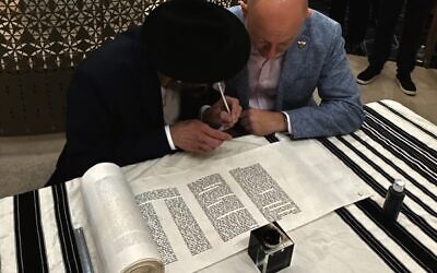 Arsen Ostrovsky (right) prepares to write letters in the Torah. Photo: Facebook