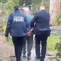 The man is led away by AFP officers. Photo: Australian Federal Police