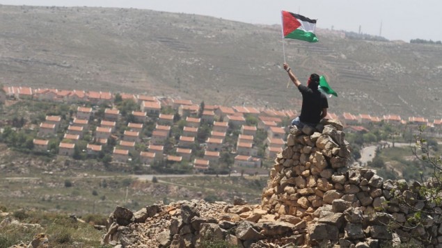 رجل فلسطيني يلوح في علم فلسطين بجانب مستوطنة عوفرا (فلاش 90)
