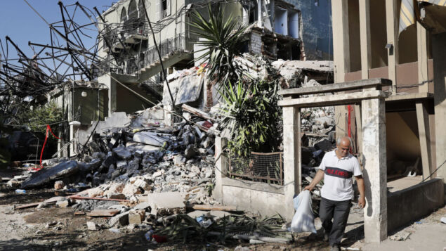 رجل لبناني يحمل أملاكه وهو يغادر منزله المدمر بالقرب من مكان وقوع انفجار في ميناء بيروت، لبنان، 6 أغسطس 2020. (Hussein Malla / AP)