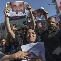 مريم بنات(67 عاما) والدة الناقد للسلطة الفلسطينية نزار بنات، تحمل ملصقا يحمل صورته في مسيرة احتجاجية على وفاته، في مدينة رام الله بالضفة الغربية، 3 يوليو، 2021. (AP Photo / Nasser Nasser)