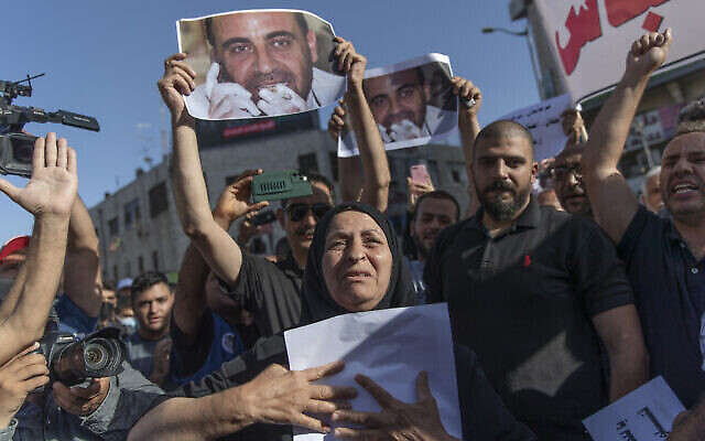 مريم بنات(67 عاما) والدة الناقد للسلطة الفلسطينية نزار بنات، تحمل ملصقا يحمل صورته في مسيرة احتجاجية على وفاته، في مدينة رام الله بالضفة الغربية، 3 يوليو، 2021. (AP Photo / Nasser Nasser)