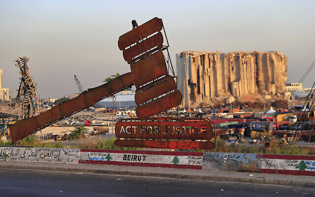 نصب يمثل العدالة يقف أمام صوامع الحبوب الشاهقة التي دمرت في انفجار هائل في أغسطس 2020 في مرفأ بيروت، لبنان، في 4 أغسطس 2021 (AP Photo / Hussein Malla ، File)