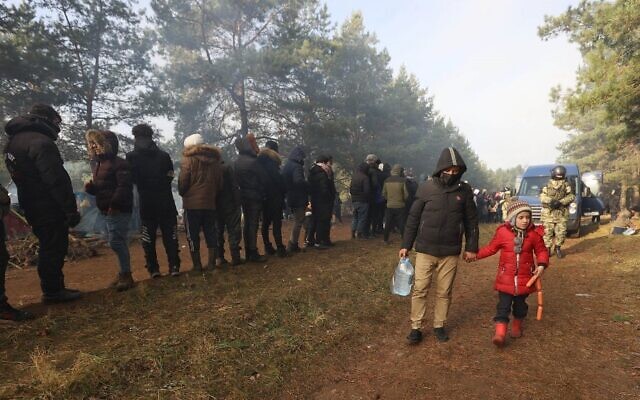 تُظهر صورة تم التقاطها في 10 نوفمبر 2021 مهاجرين يقفون في طابور لتلقي المساعدات الإنسانية التي يقدمها الصليب الأحمر البيلاروسي ومسؤولو البلاد في مخيم على الحدود البيلاروسية-البولندية في منطقة غرودنو.( Ramil NASIBULIN / BELTA / AFP)