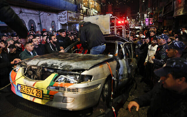 الشرطة الفلسطينية تزيل حطام سيارة إسرائيلية أضرمها حشد فلسطيني بعد أن دخل إسرائيليان مدينة رام الله بالضفة الغربية، 1 ديسمبر، 2021. (AP / Majdi Mohammed)