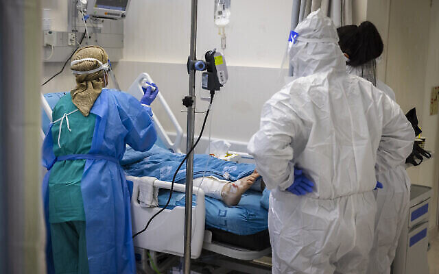 صورة توضيحية لعمال طبيين يرتدون ملابس واقية ويقدمون الرعاية لمريض في جناح كورونا في مستشفى هداسا عين كارم في القدس، 27 ديسمبر، 2021. (Olivier Fitoussi / Flash90)