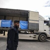 ضابط أمن فلسطيني يقف بجانب شاحنة تحمل لقاحات "سبوتنيك 5"، تبرعت بها دولة الإمارات العربية المتحدة، في مستودع تبريد في مدينة غزة، 26 يناير، 2022. (Mahmud HAMS / AFP)